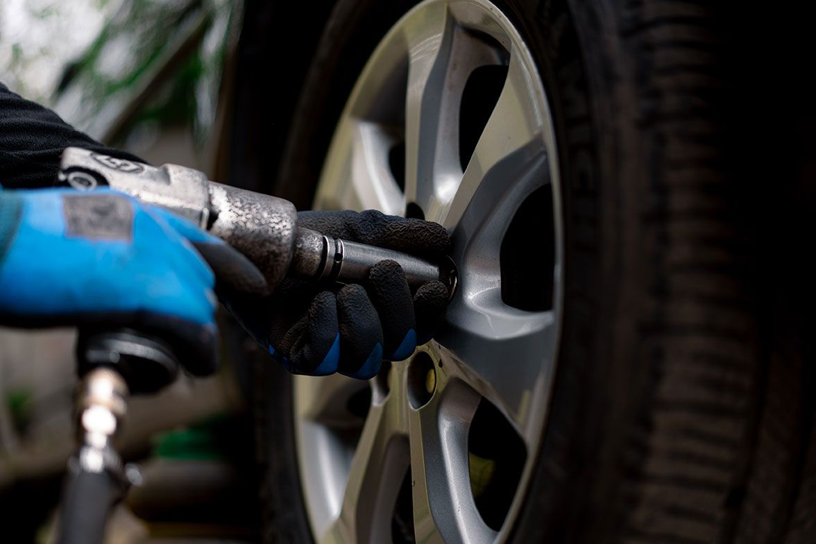 auto-mechanic-in-changing-a-wheel-from-a-black-car
